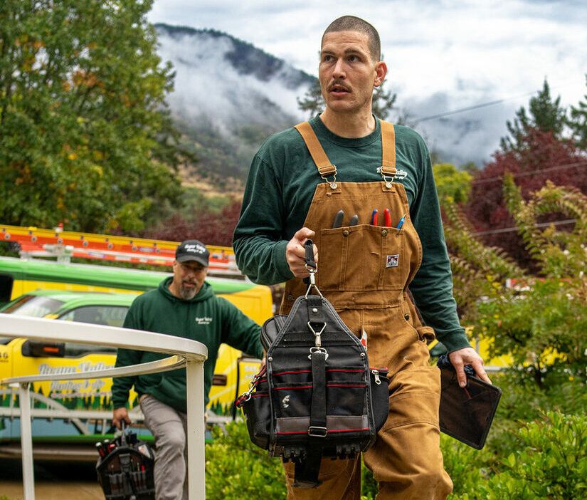 Rogue Valley Heating, Cooling & Electrical technician carrying a tool bag in Grants Pass, Oregon.