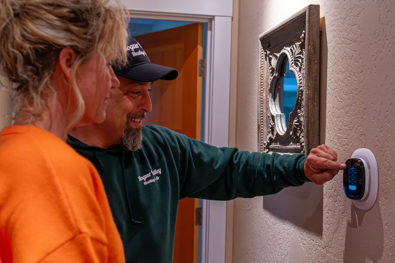 Electrician guiding a Grants Pass homeowner how to use a new thermostat after installation.