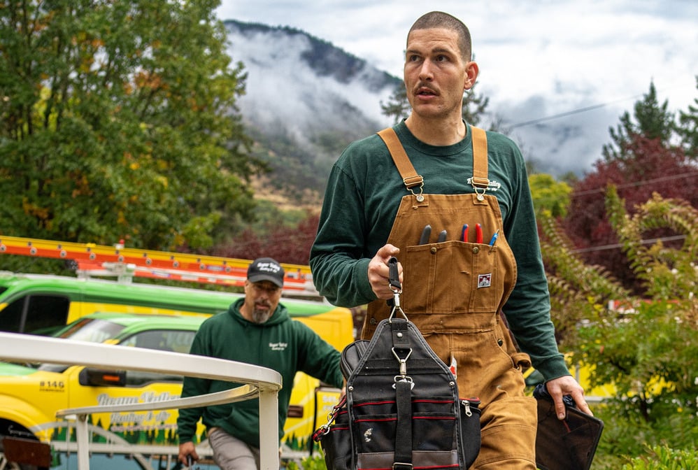 Rogue Valley Heating, Cooling & Electrical technician carrying a tool bag.